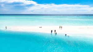 A stunning aerial view of a pristine beach in the Maldives with turquoise waters and people enjoying the sun.