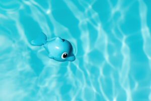 A blue toy fish floating in clear pool water, capturing summer vibes.