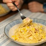 Enjoy a delicious bowl of creamy spaghetti with corn and ham, perfect for comfort dining.