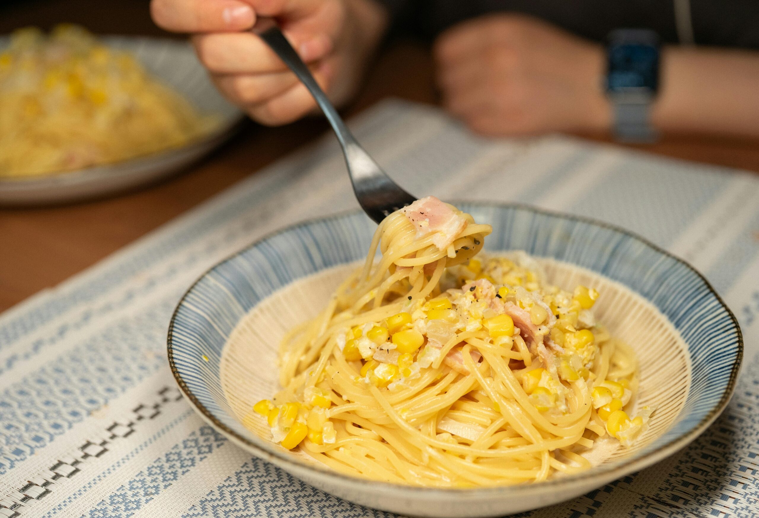 Enjoy a delicious bowl of creamy spaghetti with corn and ham, perfect for comfort dining.