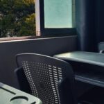 An empty classroom with desks and chairs bathed in sunlight through a window.