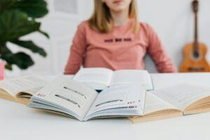 A young woman studying with open books on a white table indoors.