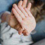 Close-up of a child's hands covering their face, creating a playful and mysterious vibe.