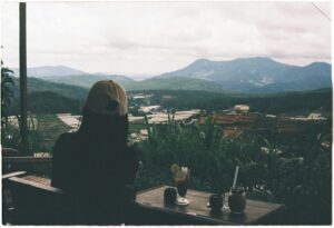 Woman sitting in cafe enjoying a mountain view with coffee. Perfect for travel inspiration.