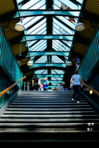 People ascending a modern subway station staircase with a glass roof and urban ambiance.