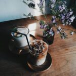 Two iced beverages with florals on a wooden table create a refreshing indoor setting.