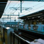 A modern train station platform with commuters waiting during the day.