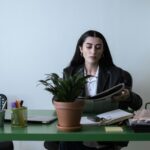 A professional woman reading a newspaper at her desk in a contemporary office setting.