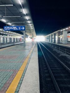 Empty train station platform with sunlight at the end of tracks and prominent signage.