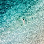 Drone shot of a woman swimming in clear blue sea off the coast of Croatia.