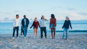 A group of diverse friends enjoying a relaxing walk on the beach during sunset.