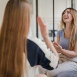 Two young women communicating with sign language indoors, expressing joy.