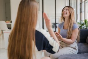 Two young women communicating with sign language indoors, expressing joy.