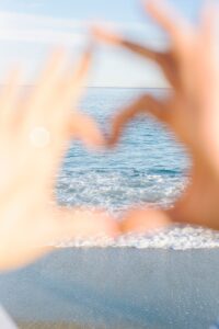 Hands forming a heart shape framing the tranquil Barcelona seaside.