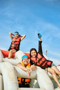 Three people enjoying a sunny day at a water park, wearing life vests and smiling.