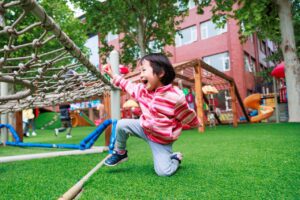 A cheerful child enjoying playtime outdoors on a bright playground.