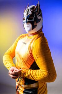 Luchador with a striking mask against a contrasting color background, showcasing Mexican wrestling culture.