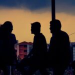 Silhouette of diverse group chatting against Bengaluru skyline at twilight.