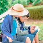 A mother and son bond while enjoying a sunny day at the park, sitting on a bench.