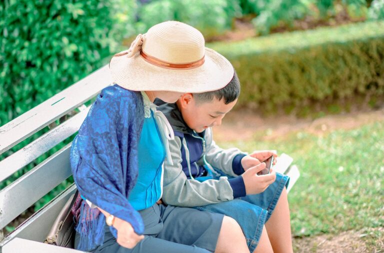 A mother and son bond while enjoying a sunny day at the park, sitting on a bench.