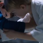 Two young boys engage in jiu jitsu training, focusing on combat skills indoors.