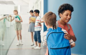 Group of kids socializing in a bright school corridor, wearing backpacks.
