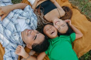 A happy family enjoying a sunny day together lying on a picnic blanket.